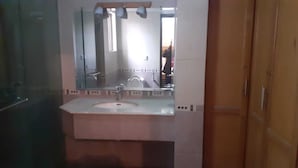 A bathroom with a white sink, a mirror, and a wooden door. - Hotel Pak Inn Gulberg (Lahore)