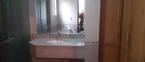 Casa de banho com uma pia branca, um espelho e uma porta de madeira.