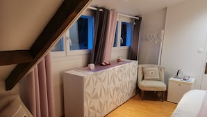 Une chambre à coucher avec un lit, un petit bureau, une chaise et une fenêtre avec des rideaux.
