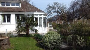 Une maison blanche avec une véranda, un palmier et un jardin bien entretenu.