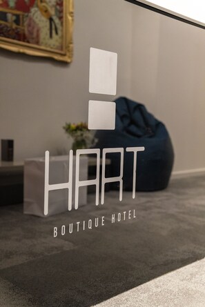 Skilt for HART Boutique Hotel med et moderne design og en blå pølesofa i baggrunden.