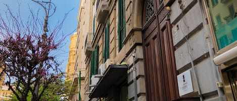 A multi-story building with a traditional architectural style, featuring balconies, air conditioning units, and a prominent entrance with a wooden door.