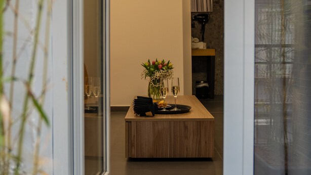 A modern kitchen with a wooden island, a vase with flowers, and a glass of wine on the counter. - Hart Boutique Rooms (Naples)
