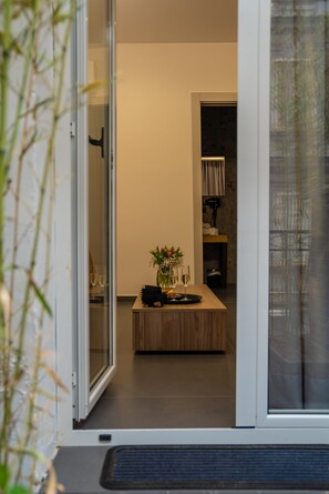 A modern kitchen with a wooden island, a vase with flowers, and a glass of wine on the counter. - Hart Boutique Rooms (Naples)
