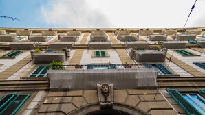 A building facade with multiple balconies, a central decorative element, and a patterned door. - Hart Boutique Rooms (Naples)
