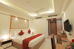Una habitación de hotel moderna con una cama grande, un escritorio, un televisor y un ventilador de techo.