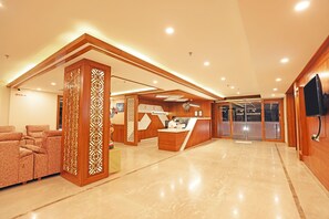 Un vestíbulo amplio con mostrador de recepción, zona de estar y un diseño moderno con detalles de madera y suelo de mármol.