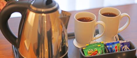 A coffee setup with a kettle, two cups, and a tray with sugar packets.
