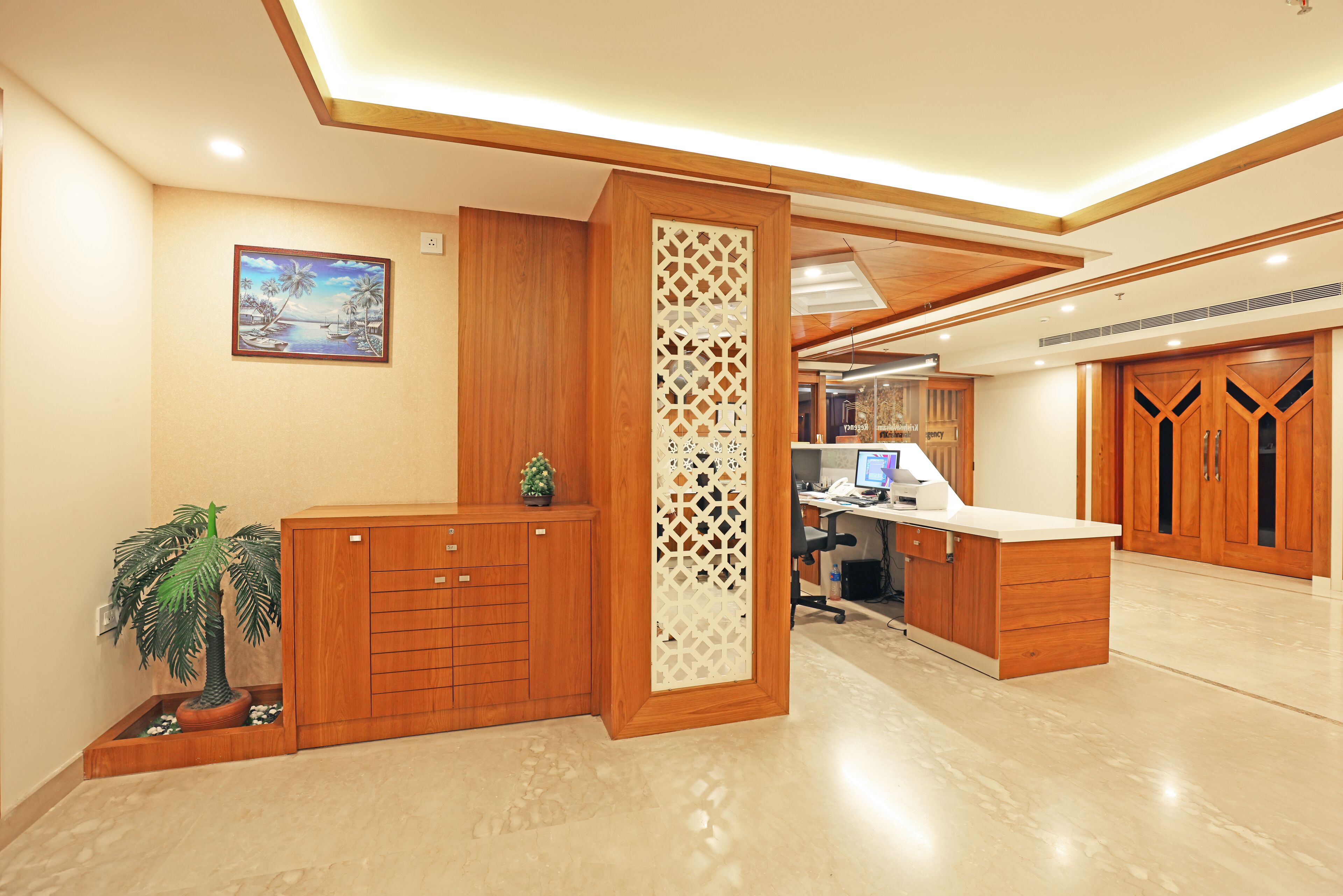 A reception desk with a wooden finish, a decorative screen, and a small potted plant.