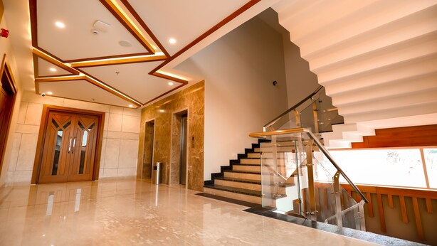 Un intérieur moderne avec un sol en marbre poli, un escalier doté de rampes en verre et un plafond au design géométrique.