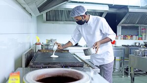 Un chef cuisinier préparant des plats dans une cuisine professionnelle.