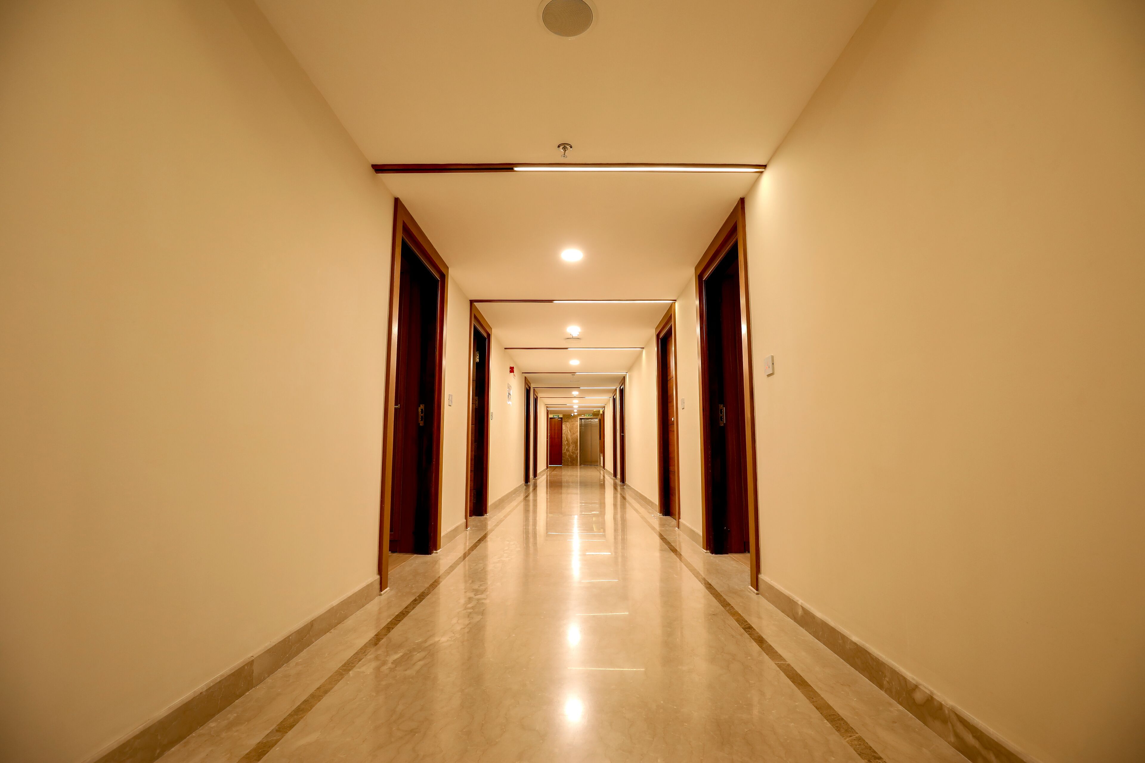 Un largo pasillo bien iluminado con puertas a ambos lados que dan a habitaciones.