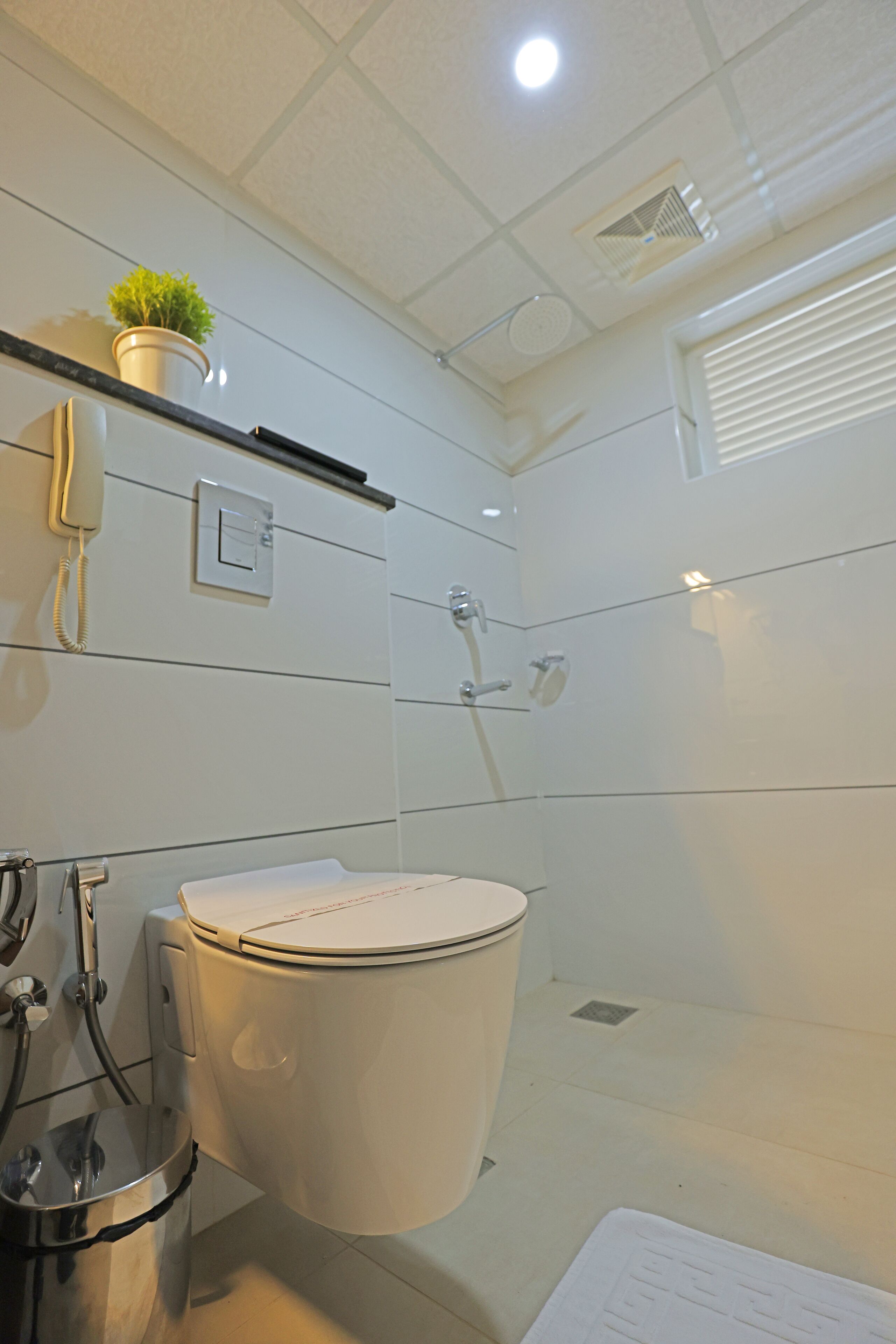 Een moderne badkamer met toilet, hygiëneschuimer en douche.