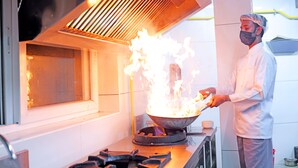 Un chef cuisinant avec des flammes dans une cuisine professionnelle.