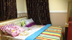 A bed with a floral bedspread, a striped blanket, and multiple pillows. - Blue-view Suites & Apartments (Abuja)