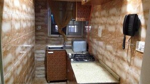A compact kitchen with a gas stove, a microwave, and a telephone. - Blue-view Suites & Apartments (Abuja)