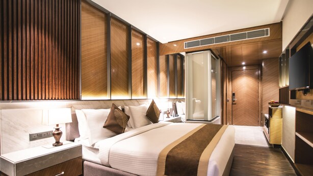 Una habitación de hotel moderna con una cama grande, una mesita de noche, un armario y un televisor.