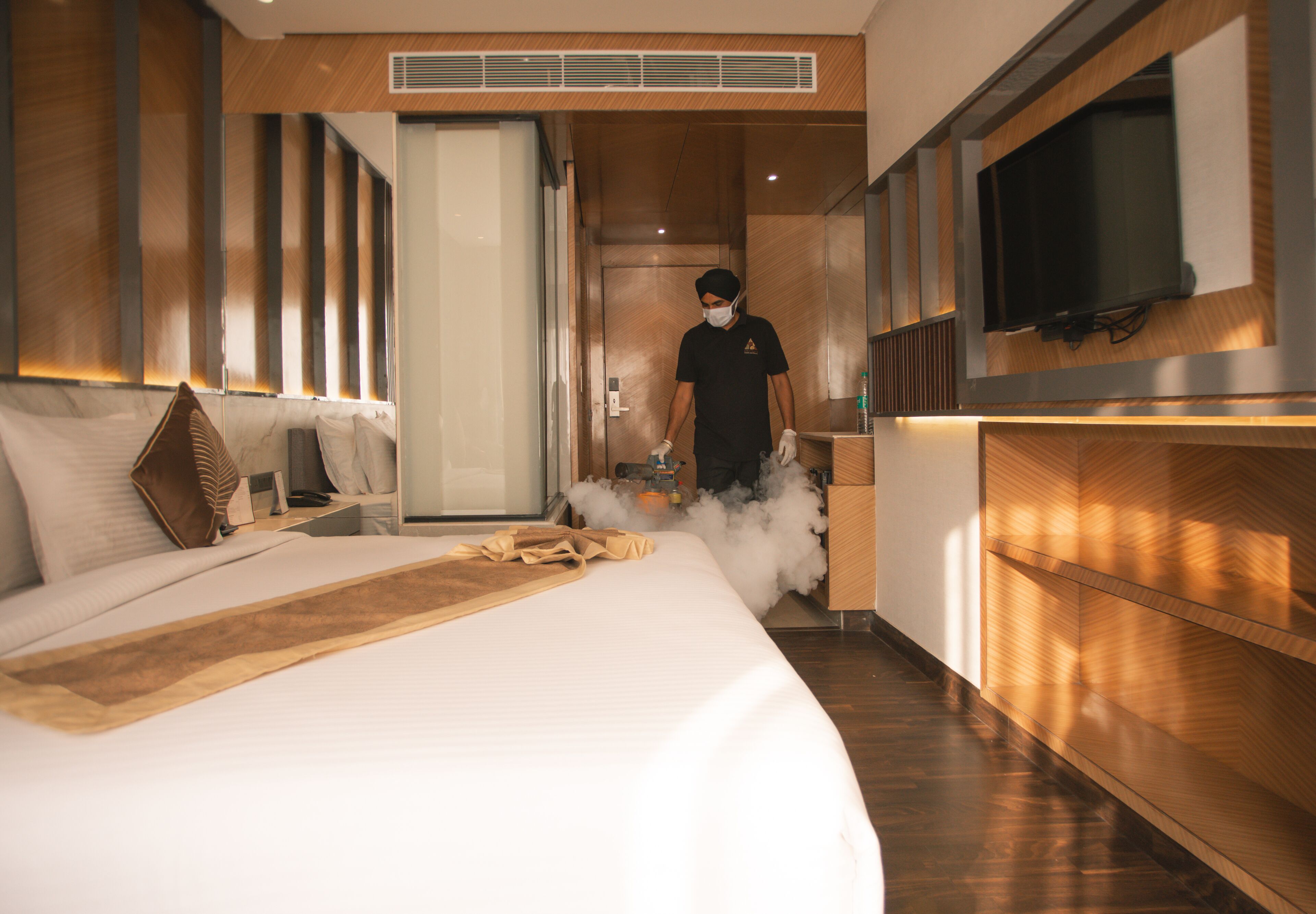 Une chambre d’hôtel moderne dotée d’un grand lit, d’une tête de lit en bois, d’un téléviseur à écran plat et d’un mini-bar.