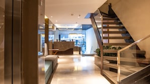 Un interior moderno con una escalera, una zona de estar y vistas al restaurante.