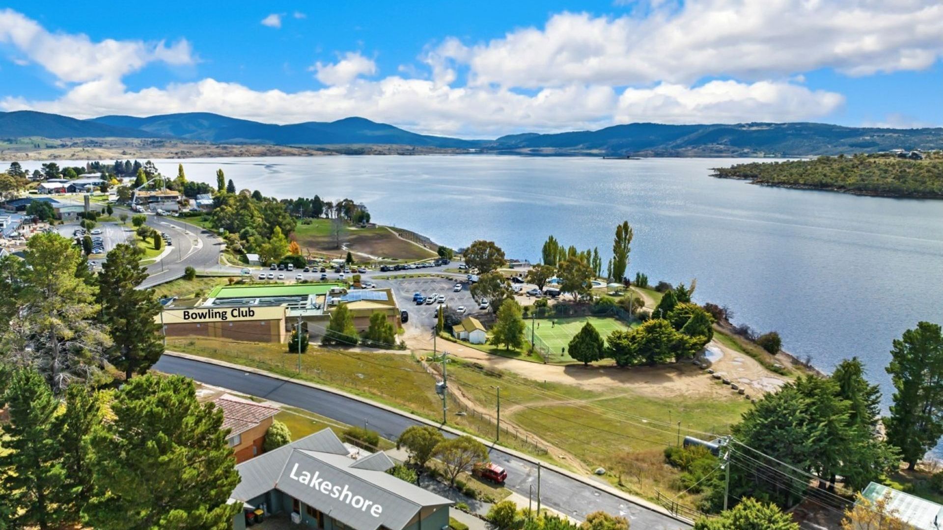 A lakeside property with a bowling club, a tennis court, and a parking area.