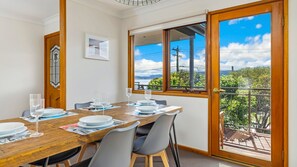 Enjoy meals in this dining area with a table for four, a framed picture, and a view of the balcony overlooking a lush landscape.