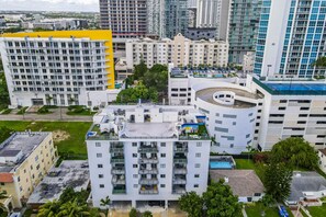 A modern multi-story building with a rooftop pool and a circular structure. - Lovely Unit Mins from Wynwood with Free Parking (Miami)
