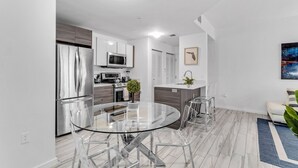 A modern kitchen with stainless steel appliances, a glass dining table, and a minimalist design. - Lovely Unit Mins from Wynwood with Free Parking (Miami)