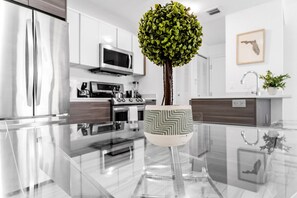 A modern kitchen with stainless steel appliances, a glass dining table, and a decorative plant in a patterned pot. - Lovely Unit Mins from Wynwood with Free Parking (Miami)