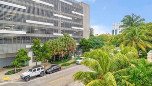 A modern building with a grid-like facade, surrounded by lush greenery and palm trees. - Lovely Unit Mins from Wynwood with Free Parking (Miami)