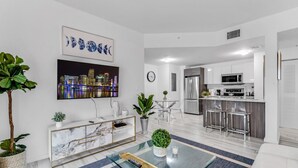 A modern living room with a marble console, a cityscape painting, and a dining area with a glass table. - Lovely Unit Mins from Wynwood with Free Parking (Miami)