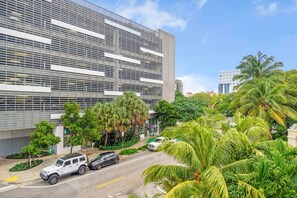 A modern building with a grid-like facade, surrounded by lush greenery and palm trees.