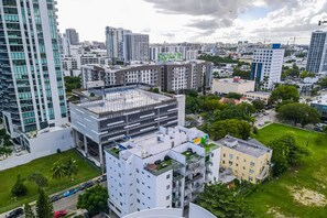 A high-rise building with multiple floors, a rooftop terrace, and surrounding urban landscape. - Lovely Unit Mins from Wynwood with Free Parking (Miami)