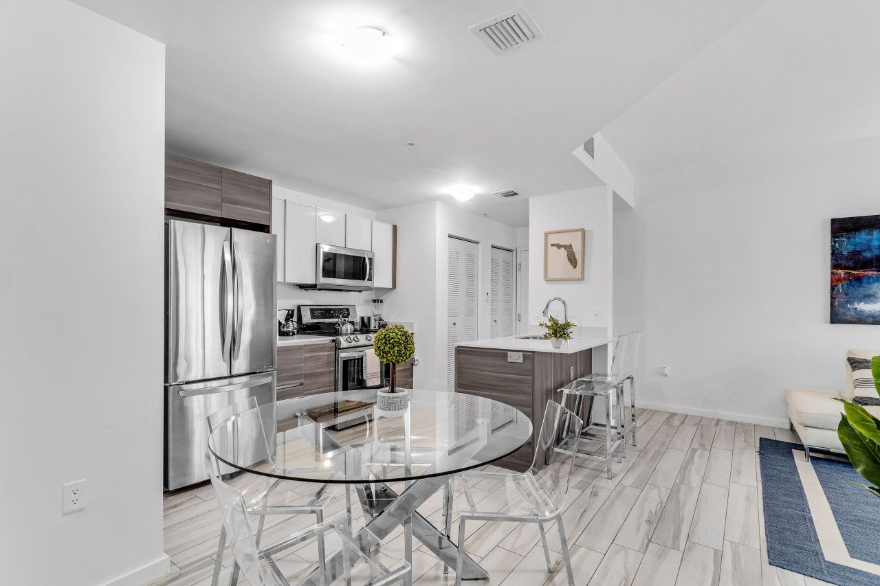 A modern kitchen with stainless steel appliances, a glass dining table, and a minimalist design.