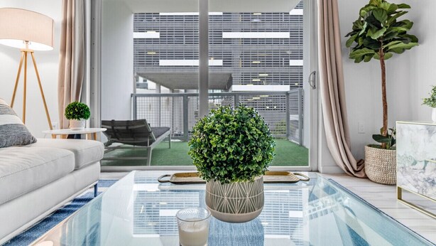 A modern living room with a glass coffee table, a sofa, a lamp, and a potted plant. - Lovely Unit Mins from Wynwood with Free Parking (Miami)
