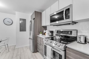 Een moderne keuken met roestvrijstalen apparatuur, een magnetron, een broodrooster en een klok aan de muur.