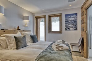 Ein Schlafzimmer mit einem Bett, Kissen, einem Sessel und einem Bild an der Wand.