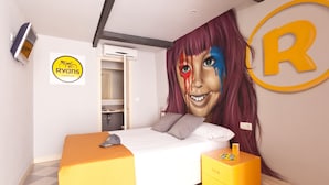 A hotel room with a bed, a nightstand, a wall-mounted TV, and a door to a bathroom. - Ryans Budget (Ibiza Town)