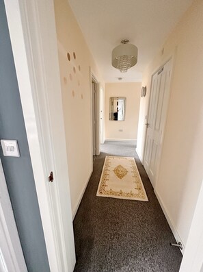 Stylish hallway leads to a room with carpeted floor and patterned rug.