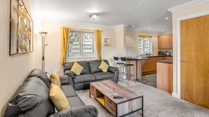 A modern living room with a grey sofa, yellow cushions, a wooden coffee table, and a kitchen in the background. - Cosy 2 Bedr house in a central Norwich with all amenities  (Norwich)