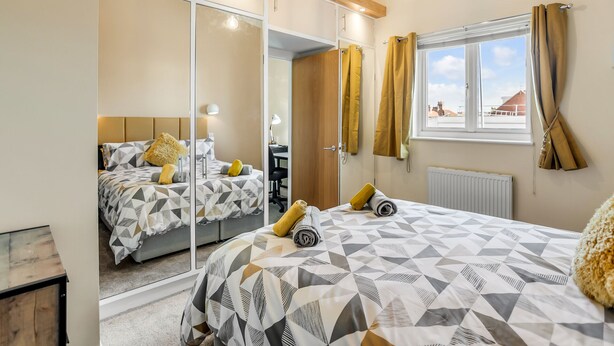 A bedroom with a bed, a mirror, a window with curtains, and a radiator. - Cosy 2 Bedr house in a central Norwich with all amenities  (Norwich)