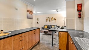 A modern kitchen with wooden cabinets, a black countertop, and a dining area with a sofa and table. - Cosy 2 Bedr house in a central Norwich with all amenities  (Norwich)