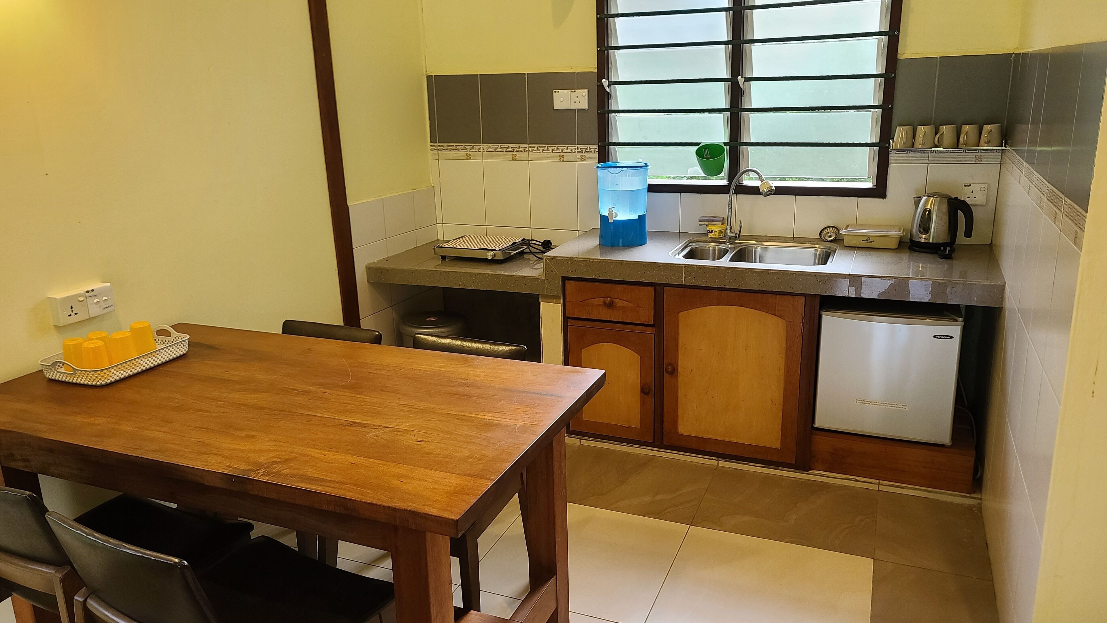 A compact kitchen with a wooden table, a sink, a stove, and a small refrigerator.