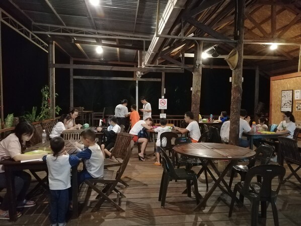 An outdoor dining area with tables and chairs, a covered roof structure, and a no-smoking sign. - Sepilok B&B (Sandakan)