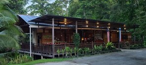 A wooden building with a covered porch, surrounded by lush greenery. - Sepilok B&B (Sandakan)