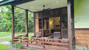 Eine hölzerne Veranda mit Deckenventilator, Tisch und zwei Stühlen.