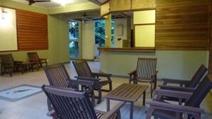 Ein Zimmer mit Holzmöbeln, darunter Stühle und ein Tisch, sowie einem Deckenventilator.
