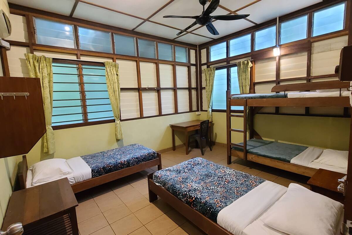 Una habitación tipo dormitorio con literas, un escritorio y una silla.