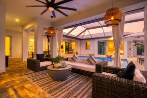 Un espacio interior amplio con piscina, muebles de mimbre y ventilador de techo.