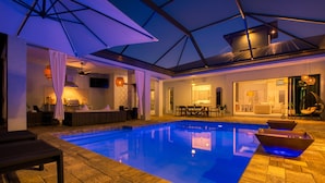 Un área interior de piscina moderna con una piscina azul cristalina, tumbonas y un comedor con vistas a la piscina.