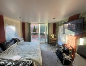 A bedroom with a bed, a TV, and a sliding glass door leading to a patio.
